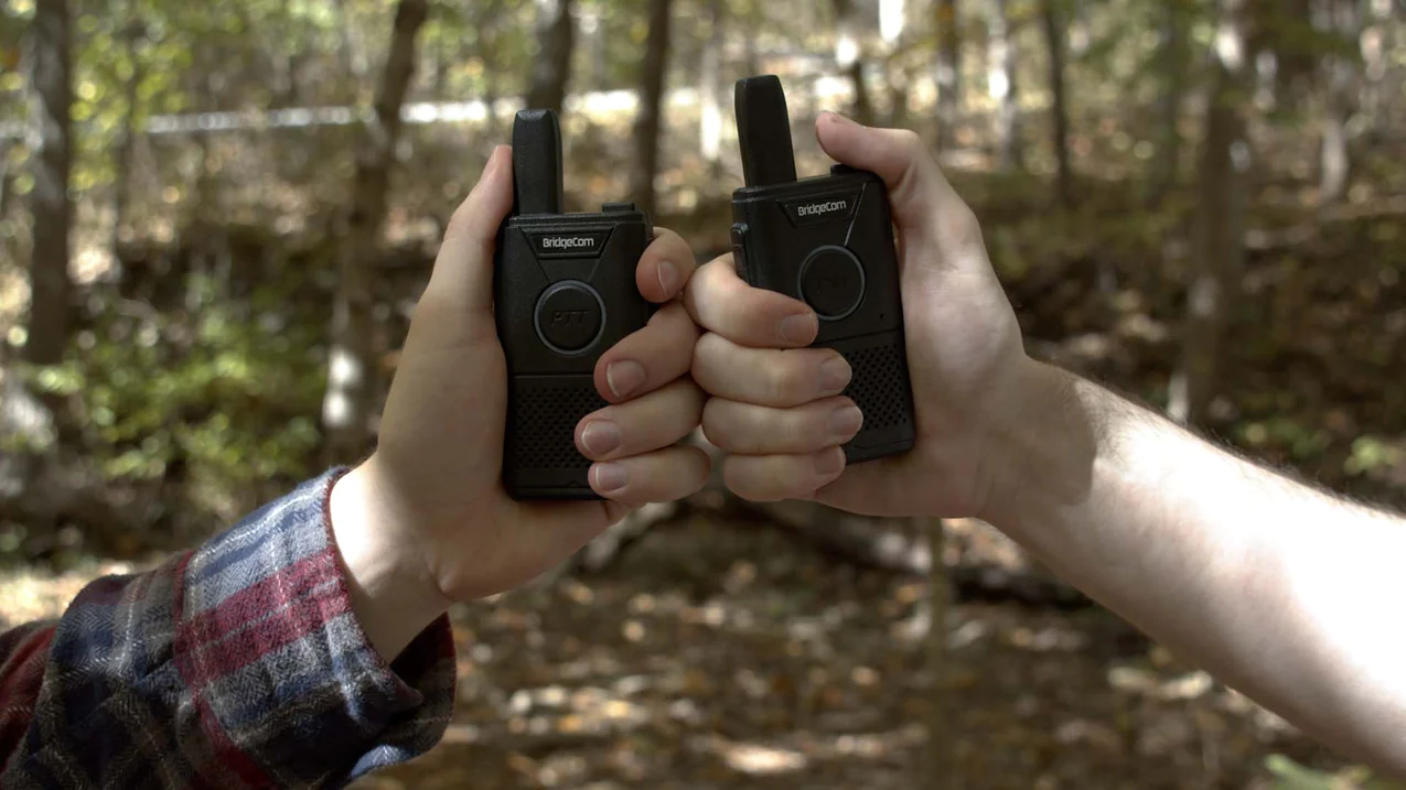BridgeCom Buddy Handheld FRS Radio Two people fist bumping with two BridgeCom Buddy Handheld FRS Radios