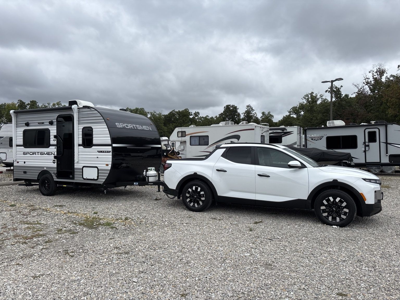 White Hyundai Santa Cruz and KZ Sportsmen Classic travel trailer parked on gravel at Nashville KOA Resort