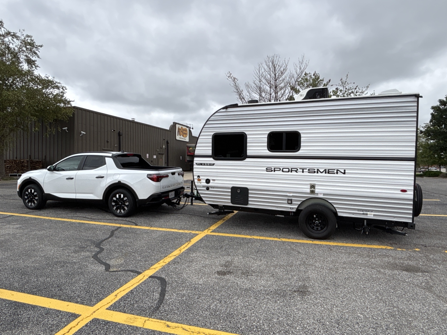 White Hyundai Santa Cruz towing a KZ Sportsmen Classic in a parking lot